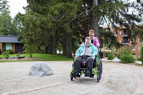 Female pushing a resident in a wheelchair through the Labyrinth