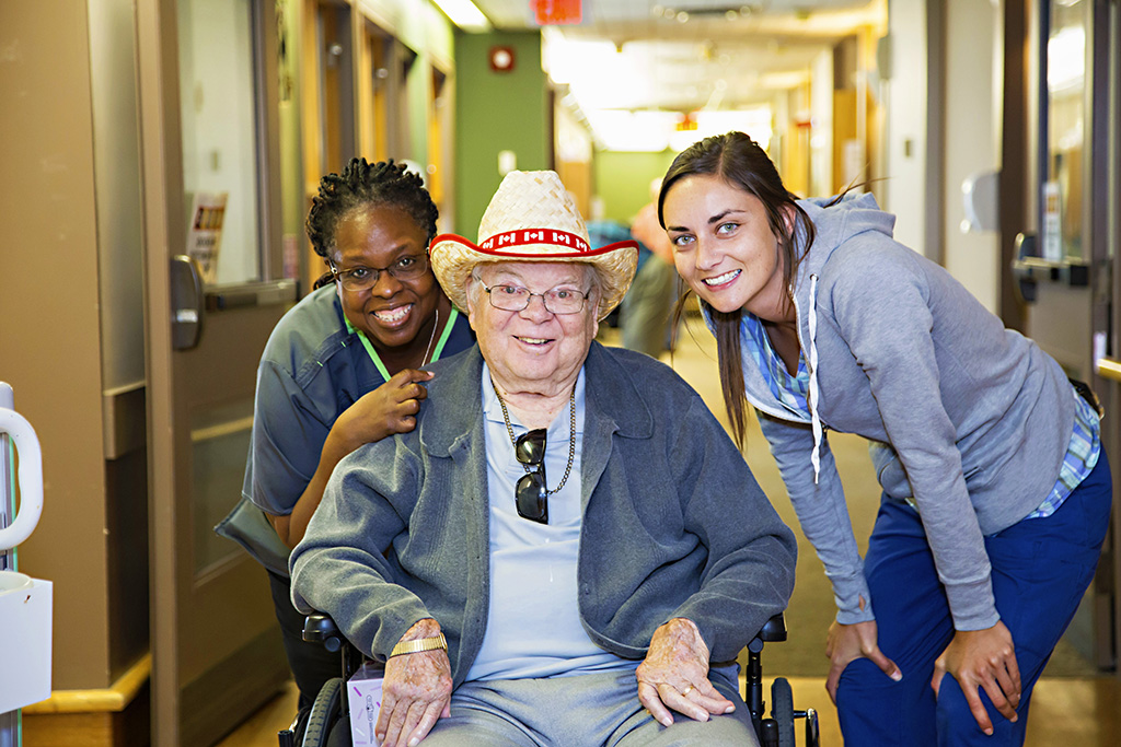 Two nursing staff membes with a male resident in a wheelchair