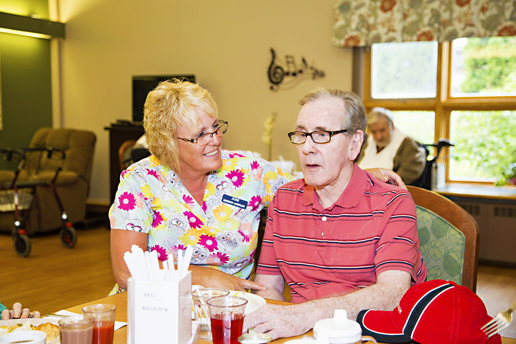 Staff member assisting a male resident during meal service