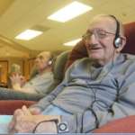 Senior Gentleman wearing headphones listening to music and smiling while relaxing in a recliner